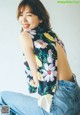 A woman sitting on the ground wearing a floral top.