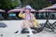 A woman with long purple hair sitting on a beach chair.