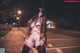 A woman in lingerie and stockings posing in a parking lot.