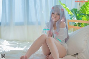 A woman sitting on a bed with her legs crossed.