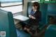 A woman in a school uniform sitting on a train.