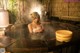 A woman in a hot tub with steam coming out of it.