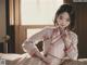 A woman in a white kimono sitting on a bed.