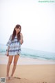 A woman standing on a beach next to the ocean.