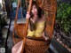 A woman in a yellow dress sitting in a wicker chair.