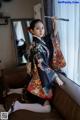 A woman in a kimono sitting on a couch holding a brush.