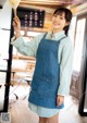 A woman in a blue apron holding a wooden spoon.