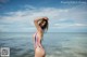 A woman in a colorful bathing suit standing in the ocean.