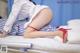 A woman in a white shirt and red stockings is laying on a hospital bed.