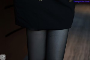 A close up of a person wearing black tights and a skirt.