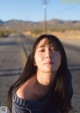 A woman sitting on the side of a road with her eyes closed.